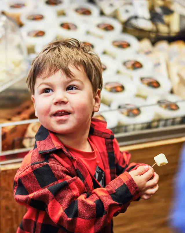 child holding a toothpick with a cheese sample