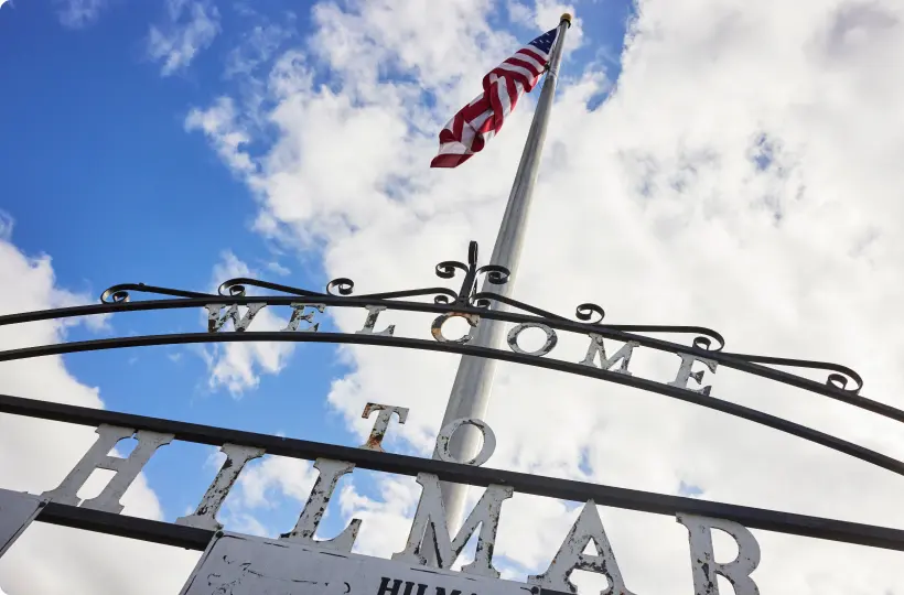 the welcome to hilmar gate with a flag