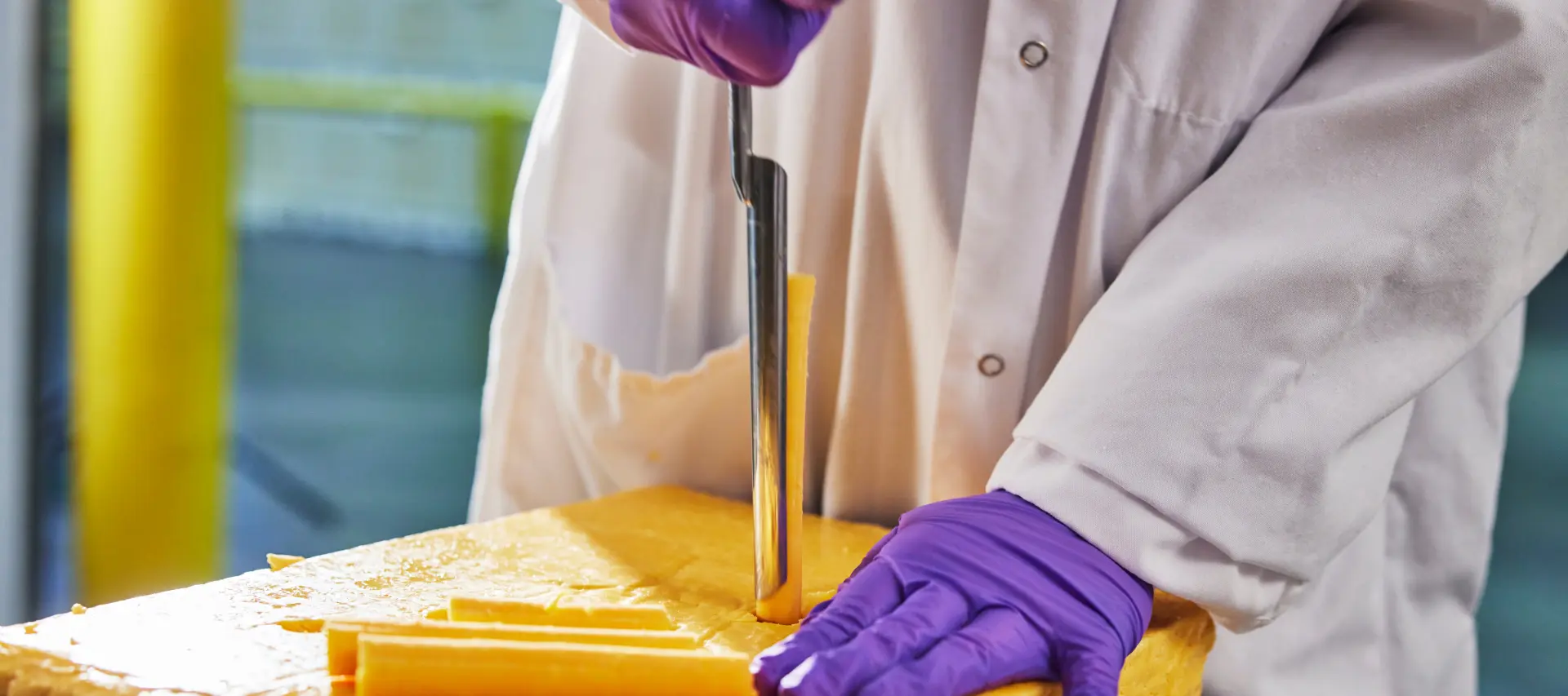 hands slicing a block of cheese