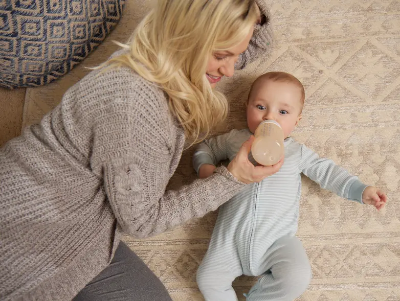 a person feeding a baby with a bottle