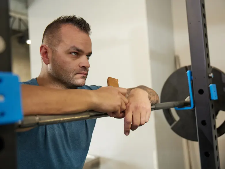 a person resting on a barbell eating a bar