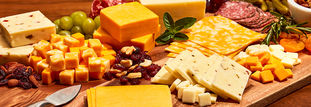 Charcuterie board featuring American-style cheeses from Hilmar, including cheddar, colby, pepper jack and monterey jack, paired with a variety of nuts, grapes, dried fruit and salami