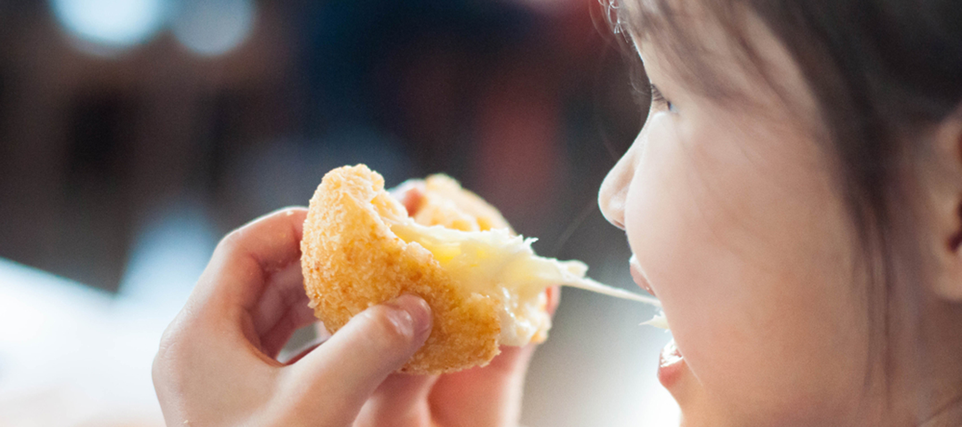 Little Asian girl eating sticky stretch fried cheese ball